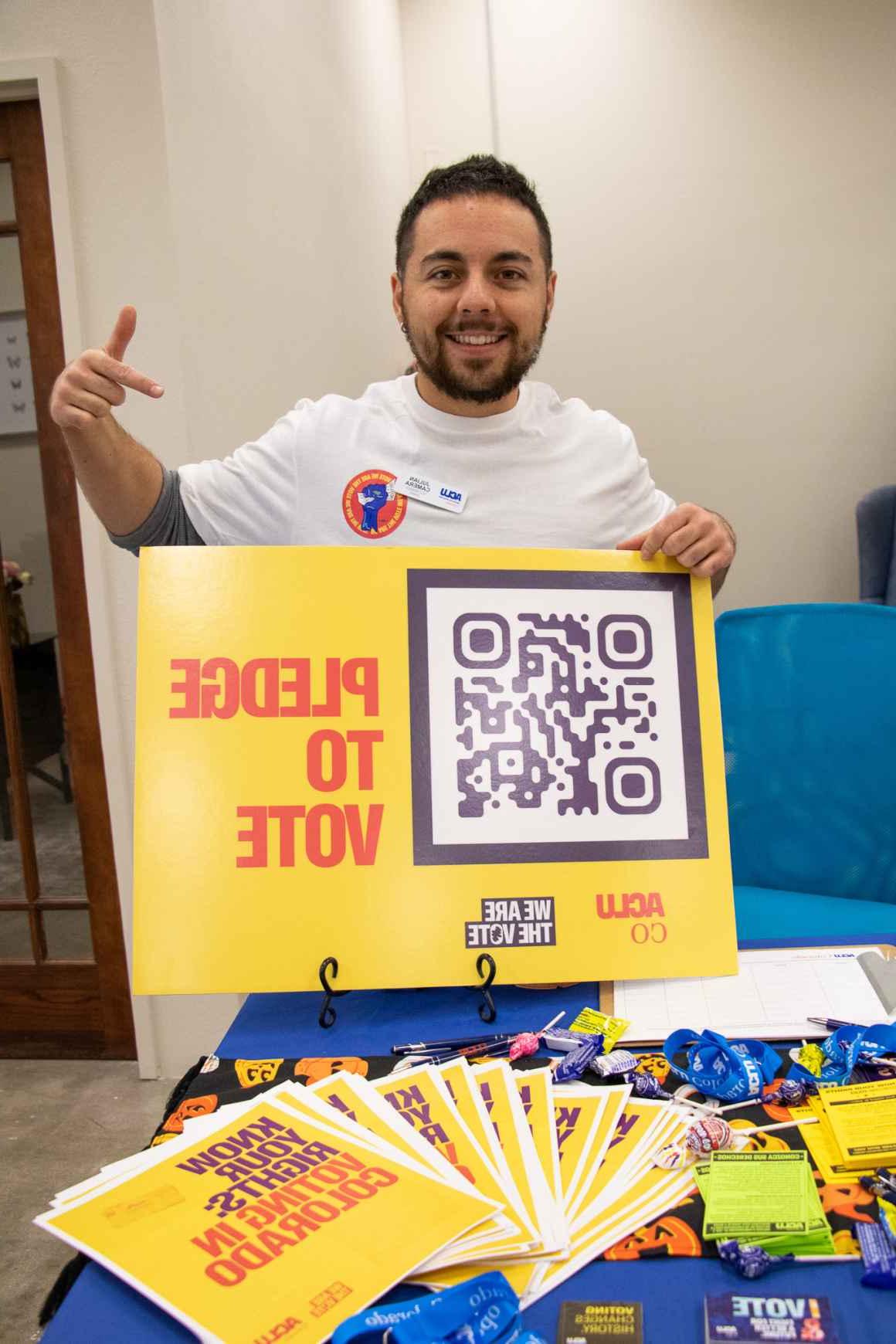 organizer holding poster with the text pledge to vote and a QR code